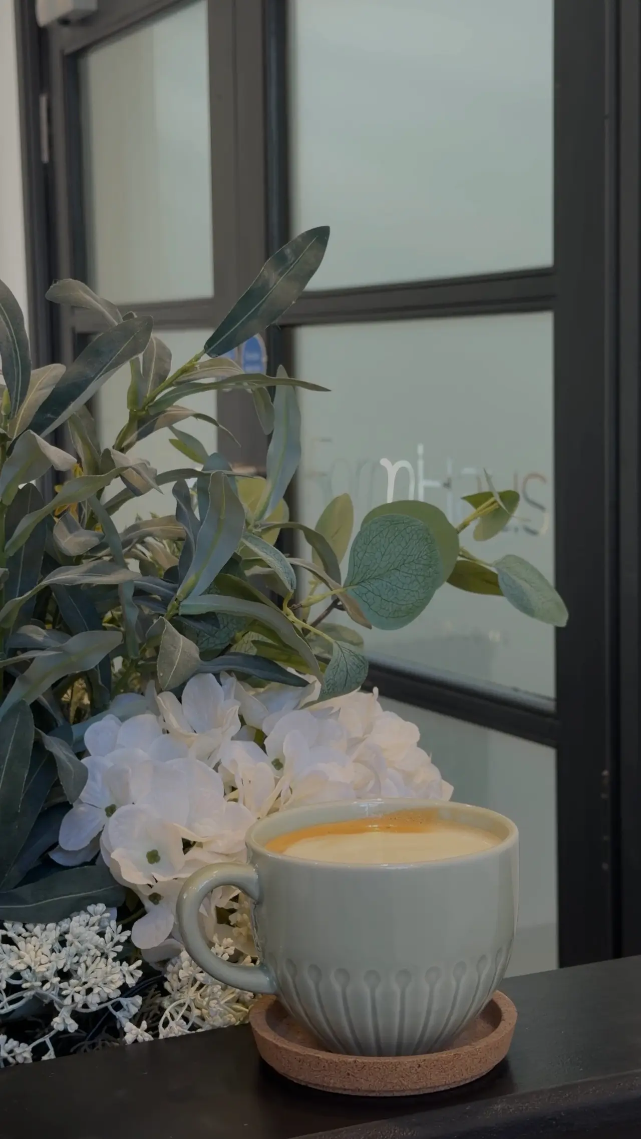 A coffee on the front desk at FormHaus, beside white flowers